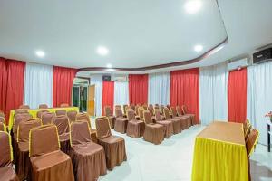 Habitación con sillas, mesas y cortinas rojas y blancas en Malibou Hotel, en Tebingtinggi