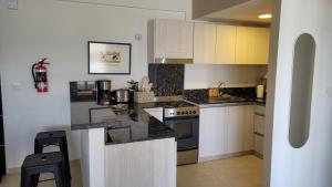 a kitchen with white cabinets and black counter tops at Departamento moderno con cochera y parrilla, amplio y luminoso in Puerto Madryn