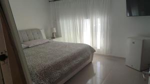 a white bedroom with a bed and a window at casa para festival vallenato in Valledupar