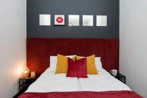 Schlafzimmer mit einem Bett mit roten und gelben Kissen in der Unterkunft City Center - Granary Island by Apartmore in Danzig
