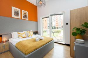 a bedroom with a large bed with an orange wall at City Center - Granary Island by Apartmore in Gdańsk