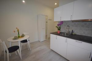 a kitchen with white cabinets and a table and a sink at Central Cracow Apartments in Kraków