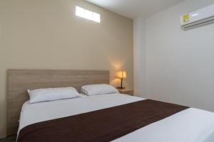 Un dormitorio con una gran cama blanca con almohadas blancas. en Genesis Hotel, en Sincelejo