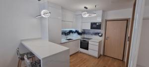 une cuisine blanche avec un comptoir et une table dans l'établissement RIVER WALK 908 ILIDZA Apartment Sarajevo, à Sarajevo