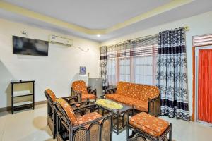 een woonkamer met een bank en een tafel en stoelen bij Malibou Hotel in Tebingtinggi