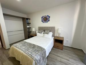 1 dormitorio con 1 cama grande con sábanas y almohadas blancas en Santuario De Luna, Departamento en Santa María Tonantzintla