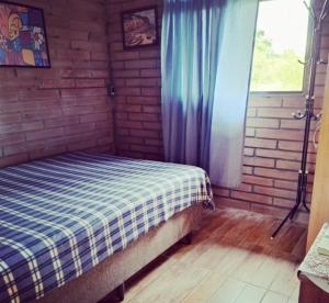 1 dormitorio con 1 cama en una pared de ladrillo en Chácara Bela Vista en Taquara