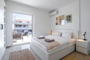 um quarto branco com uma cama e uma grande janela em Panoramic Terrace with Sunset View - Greecing em Atenas