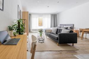 een woonkamer met een bank en een tafel met een laptop bij Apart4me Modern Apartment Geislingen zentral mit Parkplatz in Geislingen an der Steige