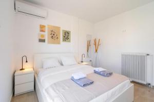 a white bedroom with two towels on a bed at Panoramic Terrace with Sunset View - Greecing in Athens