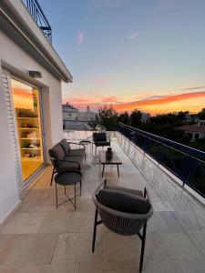 uma varanda com cadeiras e mesas e um pôr-do-sol em Panoramic Terrace with Sunset View - Greecing em Atenas