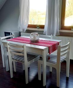 a white table and chairs with a red and white table and a window at Ferienwohnung-Ostseestrand-in-Stein-bei-Laboe in Stein