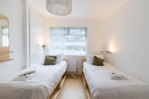 Duas camas num quarto branco com uma janela em Queens Croft Abode em Newport