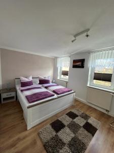 - une chambre avec un lit doté d'oreillers violets et d'un tapis dans l'établissement Ferienwohnung Streit, à Gohrisch