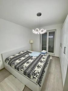 a large bed in a white room with a chandelier at Lovely flat , full furnished with free parking in Prizren