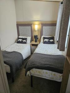 a bedroom with two beds and a table with a lamp at Roadnights Retreat in Heysham