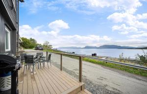 una terraza de madera con sillas, mesa y vistas al agua en AA Home Solgryveien Harstad, en Harstad