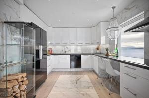 a kitchen with white cabinets and a black refrigerator at AA Home Solgryveien Harstad in Harstad