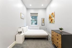 - une chambre avec un lit, une commode et une fenêtre dans l'établissement Refurbished StJohns Hill Apartment, à Londres