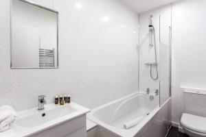 La salle de bains blanche est pourvue d'un lavabo et d'une douche. dans l'établissement Refurbished StJohns Hill Apartment, à Londres