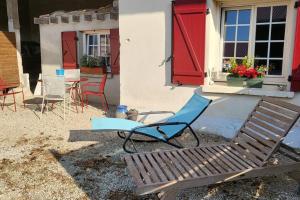 a bench and a chair in front of a house with red doors at Le moulin in Outrepont