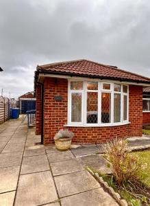 a small red brick house with a window at Nature Inspired Bungalow with 3 rooms - 10 mins from Manchester Airport in Timperley