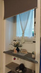 a window in a kitchen with a shelf with flowers at Nido al Mare in Bonassola