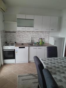 a kitchen with white cabinets and a table with chairs at Apartment Potpara in Tivat