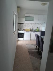 a kitchen with white cabinets and a table and chairs at Apartment Potpara in Tivat
