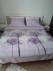 a bed with a purple and white bedspread with trees on it at Apartment Potpara in Tivat