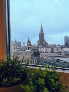 einen Blick auf die Stadt aus einem Fenster mit Pflanzen in der Unterkunft Skyline Panorama Residence Warsaw in Warschau