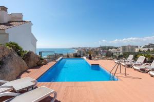 a swimming pool with chairs and the ocean in the background at Modern townhouse with stunning view in Fuengirola