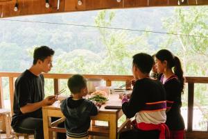 a group of people sitting around a table eating food at A Hòa Homestay in Ye Yen Sun Cay