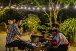 un grupo de personas sentadas alrededor de una mesa comiendo comida en A Hòa Homestay, en Ye Yen Sun Cay