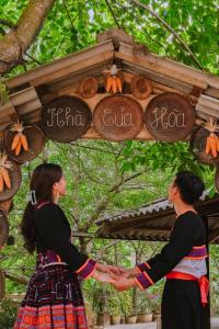two women are shaking hands under a sign with pumpkins at A Hòa Homestay in Ye Yen Sun Cay