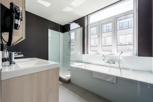 La salle de bains est pourvue d'un lavabo, d'une douche et d'une baignoire. dans l'établissement Smartflats Design - Cathédrale, à Liège