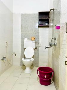 a bathroom with a toilet and a red bucket at sai bliss in Puttaparthi