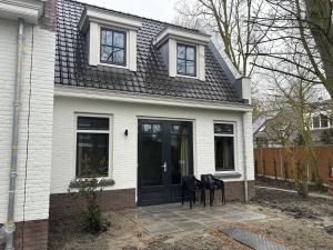 Casa blanca con puertas negras y sillas negras en Les Maisons Domburg, en Domburg