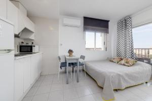 a bedroom with a bed and a table and a kitchen at Estudio Jardín del Mar in Torrevieja