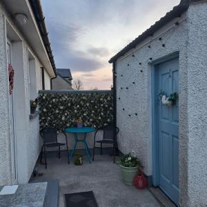 a patio with a blue door and chairs and a table at Red Gate Cottage in Buncrana