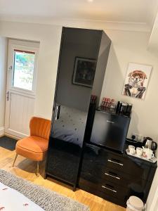 a large black cabinet with a chair in a room at Foxes Den at Foxesway in Kirkby on Bain