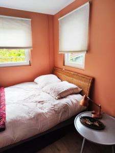 Schlafzimmer mit orangefarbenen Wänden und einem Bett mit einem Tisch in der Unterkunft Peaceful green setting near to Paris Center in Pantin