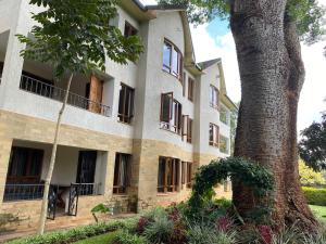 einen Blick nach außen auf ein Gebäude mit einem Baum in der Unterkunft Runda two bedroom in Nairobi