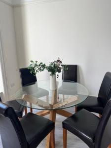 uma mesa de vidro com cadeiras pretas e um vaso com flores em Spires entire studio em Dublin