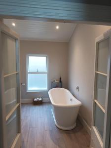 La salle de bains est pourvue d'une grande baignoire blanche et d'une fenêtre. dans l'établissement Eglinton Road - Sleeps 6 on room only basis, à Bray