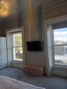 a bedroom with a tv on the wall and two windows at Eglinton Road - Sleeps 6 on room only basis in Bray
