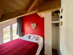 a bedroom with a red wall with a bed in it at Chalet Red Mount - Esprit chalet au pied des pistes in Les Deux Alpes