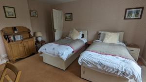 a bedroom with two beds and a dresser at Hazler Lodge in Church Stretton