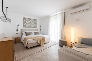 Casa Malìa Luxury Guest House في لوز: غرفة نوم بيضاء مع سرير وأريكة
