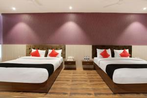 two beds in a hotel room with red pillows at S B Excellency in Jodhpur